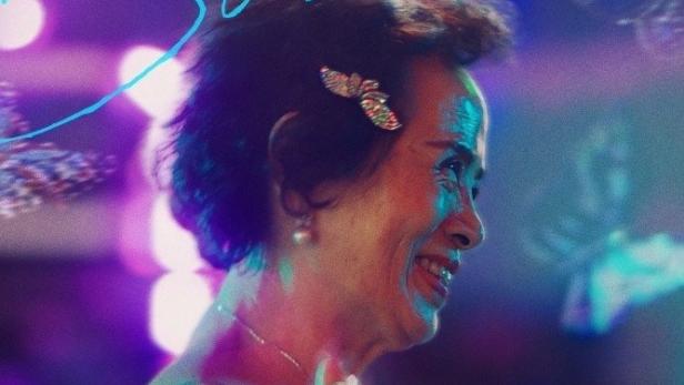 Das Filmplakat für „First Summer“ zeigt eine ältere Frau im Profil vor einem verschwommenen, farbenfrohen Hintergrund.