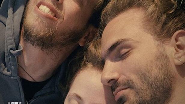 Das Filmplakat für „Die zärtliche Revolution“ zeigt drei junge Menschen, die im Gras liegen.