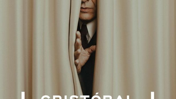 Ein Mann blickt durch einen Vorhang, im Vordergrund der Schriftzug „Cristóbal Balenciaga“.