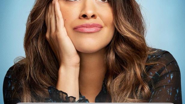 Eine Frau blickt mit Laptop, auf dem „Noch nicht ganz tot“ steht, nach oben.