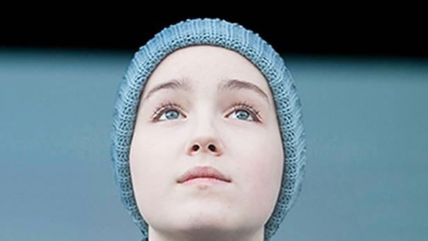 Eine junge Frau mit blauen Augen und Mütze blickt nach oben, über ihr steht der Name „Jenny“.