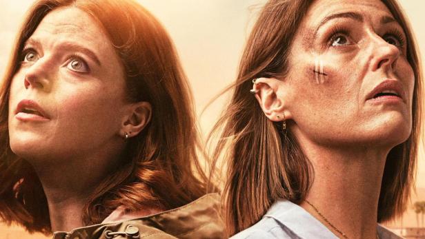 Zwei Frauen blicken besorgt in den Himmel, wo Drohnen zu sehen sind.