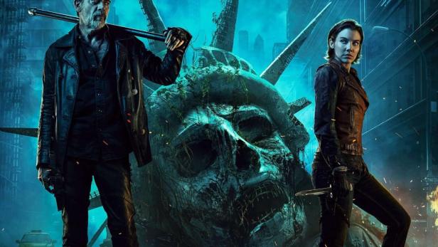 Ein Mann mit einem Stock und eine Frau mit einem Messer stehen vor einem zerstörten Freiheitsstatue-Kopf in „The Walking Dead: Dead City“.