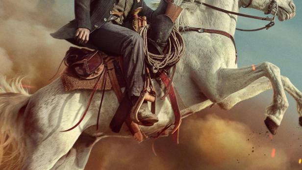 Ein Mann, vermutlich Bass Reeves, reitet auf einem weißen Pferd vor einem staubigen Hintergrund.