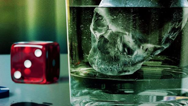 Ein Totenkopf-Eiswürfel schwimmt in einem Glas Wasser, daneben ein roter Würfel. Im Vordergrund steht „CSI: Vegas“.