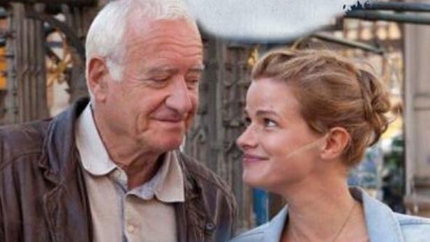 Ein älterer Mann und eine jüngere Frau schauen sich auf dem Poster zu „Fuchs und Gans“ an.