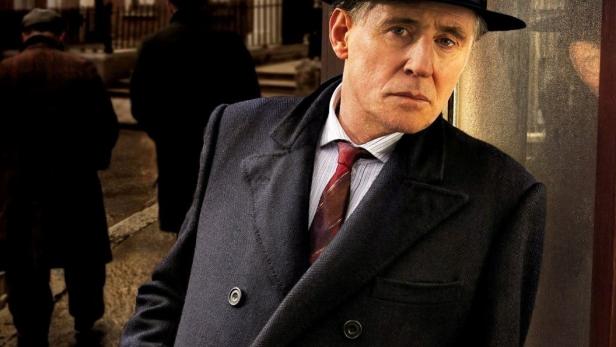 Gabriel Byrne als „Quirke“ vor einer Dubliner Straßenszene.