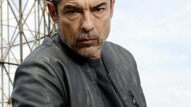 Ein Mann in Lederjacke vor einem Sendemast, möglicherweise eine Filmszene.