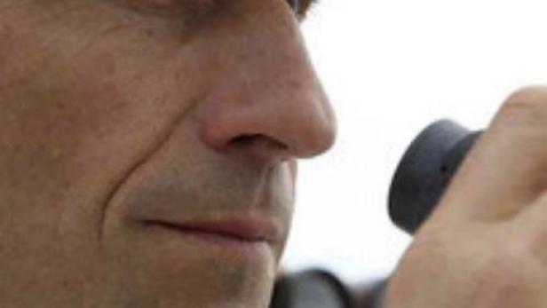 Ein Mann in Marineuniform blickt durch ein Fernglas.