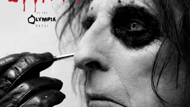 Schwarz-Weiß-Porträt von Alice Cooper, der sich mit einem Pinsel das Make-up aufträgt.