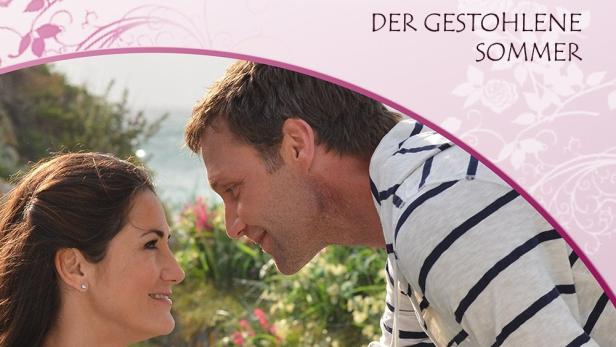 Ein Paar blickt sich verliebt vor dem Hintergrund der „Rosamunde Pilcher Collection“ an.