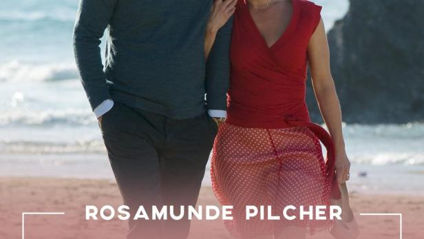 Ein älteres Paar geht am Strand entlang, möglicherweise eine Szene aus „Gefährliche Brandung“ von Rosamunde Pilcher.