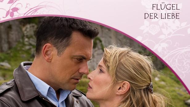 Ein Mann und eine Frau umarmen sich auf dem Cover von Rosamunde Pilchers „Flügel der Liebe“.