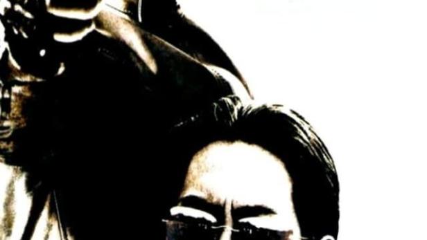 Ein Mann mit Sonnenbrille und ein Mann mit einer Pistole, vermutlich eine Filmszene.