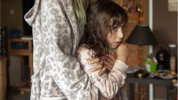 Eine besorgte Frau umarmt ein ängstliches kleines Mädchen.