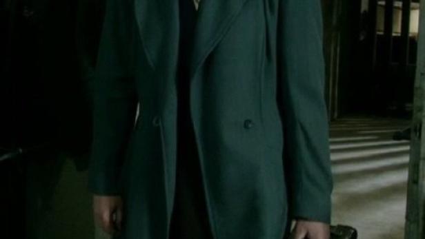 Eine Frau mit Mantel und Koffer, möglicherweise auf der Flucht.