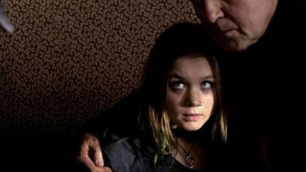 Ein Mann bedroht eine junge Frau mit einer Pistole.