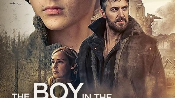 Das Filmplakat für „The Boy in the Woods“ zeigt einen Jungen, einen Mann und eine Frau vor einer zerstörten Landschaft.