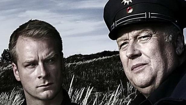 Das Filmplakat zu „Finn Zehender“ zeigt Hinnerk Schönemann und einen Polizisten vor einer Dünenlandschaft.