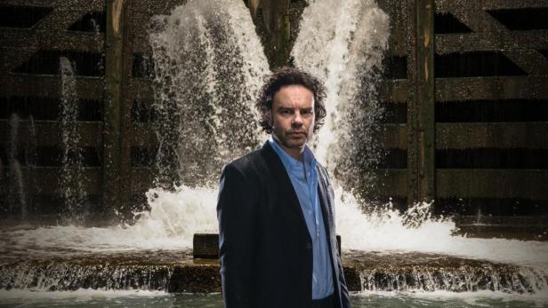 Ein Mann steht im Wasser vor einem Schleusentor, über dem der Titel „Over Water“ steht.