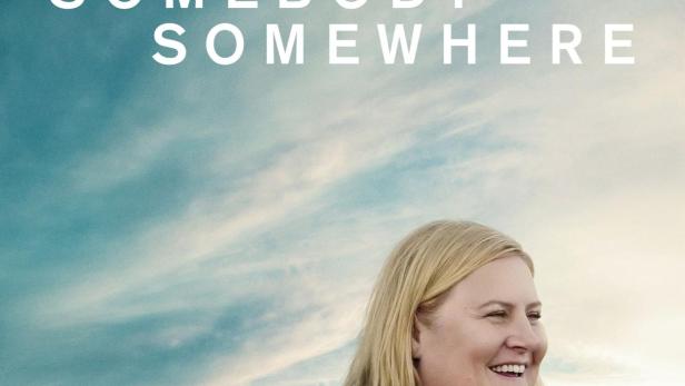 Das Filmplakat für „Somebody Somewhere“ zeigt eine lächelnde Frau vor einer ländlichen Kulisse.