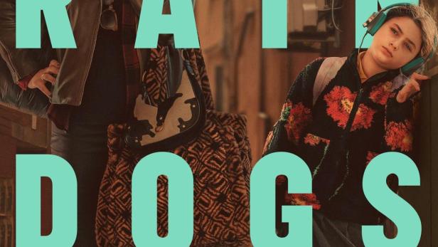 Zwei Frauen stehen vor dem Schriftzug „Rain Dogs“ in einer Gasse.