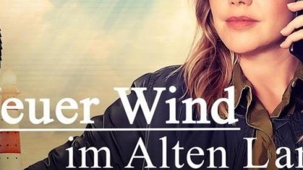 Eine Frau telefoniert vor dem Hintergrund des Titelbilds „Feuer Wind im Alten Land“.