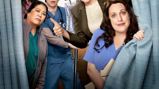 Das Ensemble der Fernsehserie „St. Denis Medical“ blickt hinter einem Vorhang hervor.