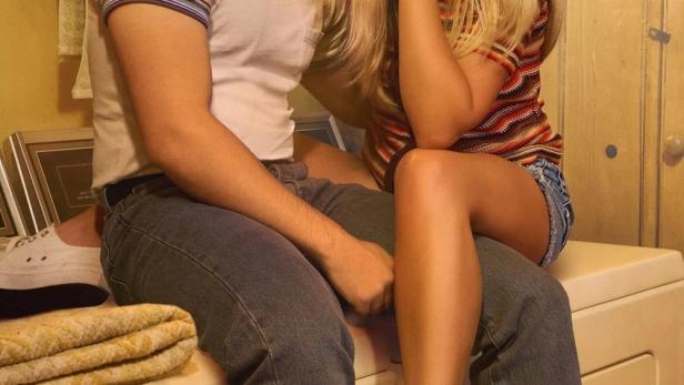 Ein junges Paar, Georgie und Mandy, sitzt auf einer Waschmaschine.