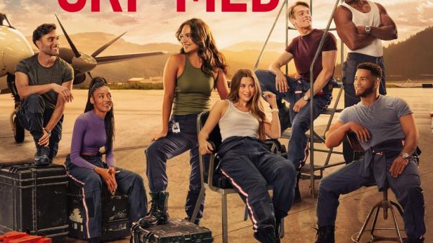 Die Besetzung der Fernsehserie „SkyMed“ posiert vor einem Flugzeug in einem Hangar.