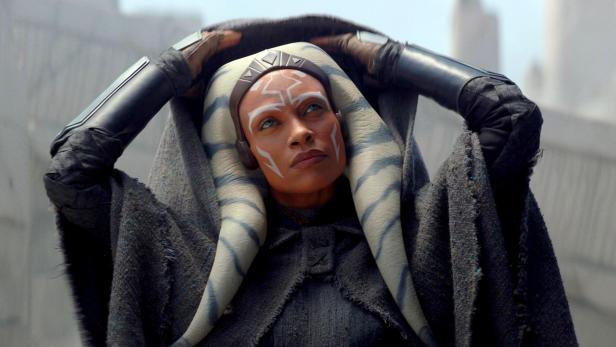 Ahsoka Tano, eine Togruta, mit blau-weissen Lekku und Gesichtsbemalung, blickt nach oben.