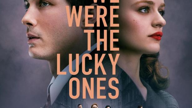 Das Filmplakat für „We Were the Lucky Ones“ zeigt die Porträts zweier junger Menschen vor einer Gruppe von Personen.