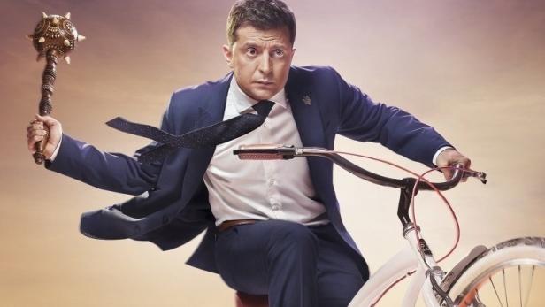 Der Schauspieler Wolodymyr Selenskyj auf dem Filmplakat zu „Слуга народу 2“ auf einem Fahrrad.