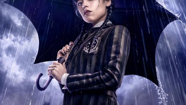 Jenna Ortega als Wednesday Addams im Regen mit einem Regenschirm.