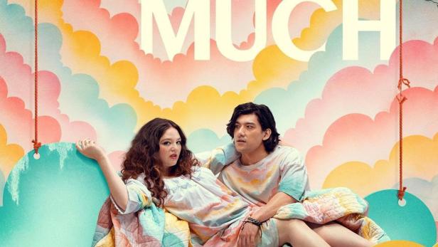 Ein Mann und eine Frau liegen auf einer Wolke vor einem bunten, bewölkten Hintergrund für „Too Much“.