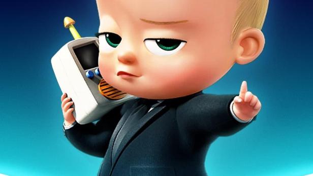 Das Boss Baby im Anzug mit einem Spielzeugtelefon am Ohr.