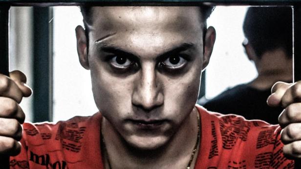 Ein junger Mann blickt ernst hinter Gittern hervor, vermutlich eine Szene aus „Mare Fuori“.