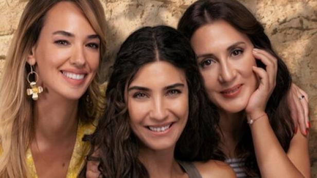 Drei lächelnde Frauen posieren vor einer Wand für das Netflix-Drama „Ein anderes Selbst“.