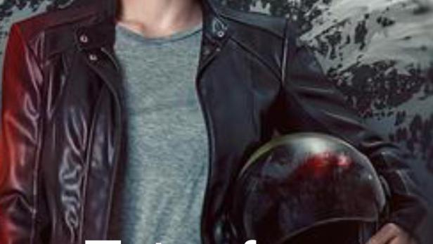 Eine Frau in Lederjacke hält einen Motorradhelm vor einer Bergkulisse.