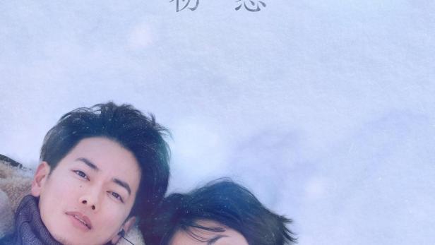 Ein junges Paar liegt im Schnee, Titel des Bildes ist „First Love“.