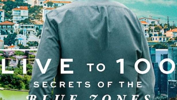 Ein Mann blickt auf eine Stadt am Meer, im Hintergrund Berge; Titelbild von „Live to 100: Secrets of the Blue Zones“.