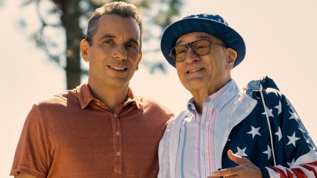 Zwei Männer, der ältere mit Hut und Jacke mit Sternenmuster, stehen nebeneinander.