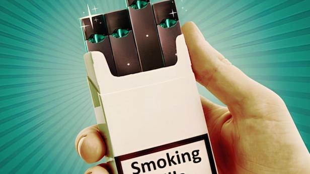 Eine Hand hält eine Packung mit E-Zigaretten vor einem türkisfarbenen Hintergrund. Auf der Packung steht „Smoking kills“.