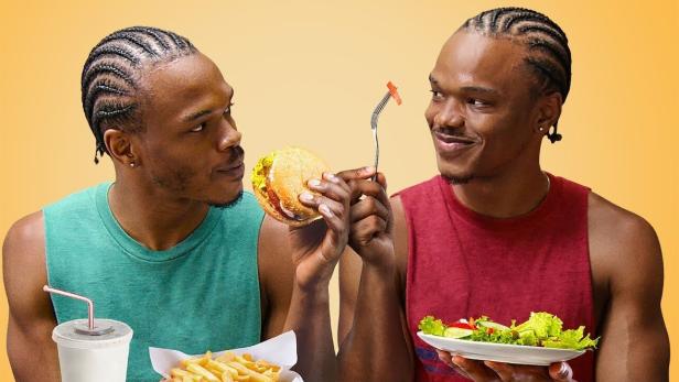 Zwei Zwillinge sitzen an einem Tisch, der eine isst einen Burger mit Pommes, der andere einen Salat.