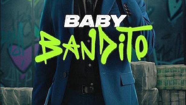 Ein Mann in einem blauen Anzug und Sonnenbrille hält ein Skateboard.