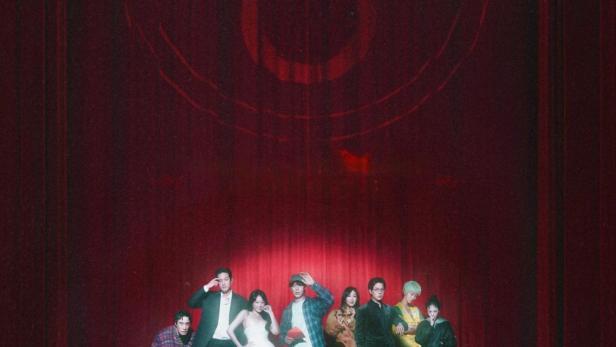 Das Ensemble von „The 8 Show“ steht vor einem roten Vorhang.