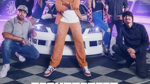 Die Besetzung von „Resurrected Rides“ posiert vor einer Reihe von Autos.