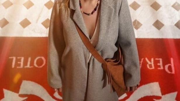 Eine Frau steht vor einem roten Teppich mit dem Titel „Mitternacht im Pera Palace“.