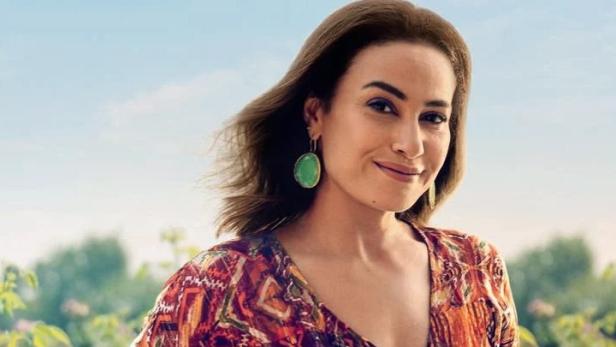 Eine Frau steht vor einem Feld mit rosa Blumen.