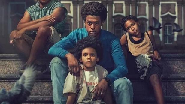 Das Filmplakat für „Os Quatro da Candelária“ zeigt vier Jungen vor der Candelária-Kirche in Rio de Janeiro.